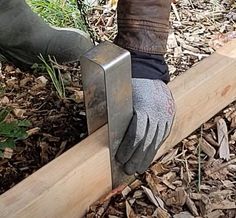 a person wearing gloves and holding a piece of wood in their hand while working on a fence post