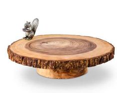 a small squirrel figurine sitting on top of a tree stump cake plate,