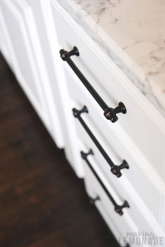 a white cabinet with two black handles and marble counter top in a kitchen or dining room