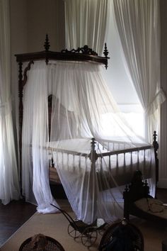 a canopy bed in a bedroom with white curtains