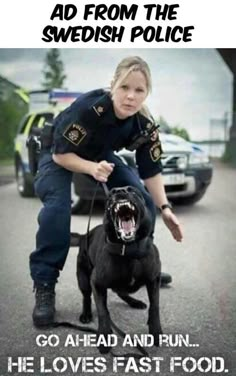 a police officer kneeling down next to a black dog with it's mouth open