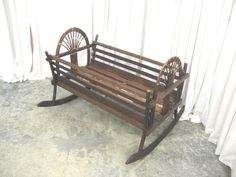 a wooden rocking chair sitting on top of a cement floor next to a white curtain