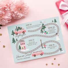 a pink and blue christmas card with a road map on it next to some flowers