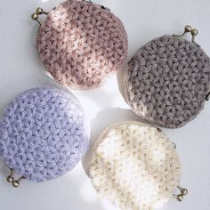 four crocheted round purses sitting next to each other on a white surface