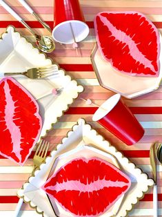 two plates with red lips painted on them and silverware next to forks, knives and spoons