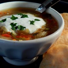 a white bowl filled with soup next to tortilla chips on a black surface