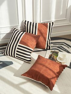 two orange and black pillows sitting on top of a white rug next to a book