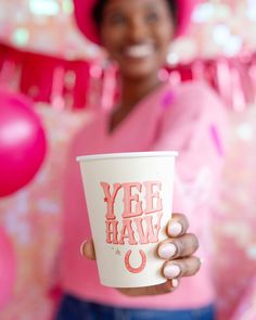 a woman holding up a coffee cup with the words yee haw on it