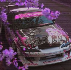 a car parked next to purple flowers on the street