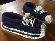 a pair of blue and white crocheted shoes sitting on top of a wooden table