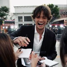 a man in a suit signing autographs for people