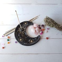 the moon is next to some incense sticks and beads on a white wooden surface with tiny stars