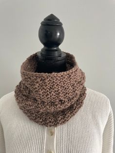 a woman wearing a brown knitted cowl with buttons on the collar and neck