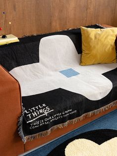 a couch covered in a blanket and pillows with the words little things written on it