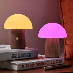 two wooden lamps sitting on top of a book next to a lamp that looks like an mushroom