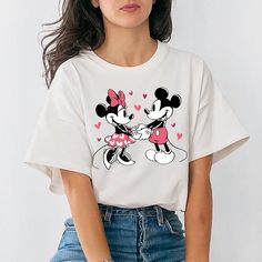 a woman wearing a mickey and minnie mouse t - shirt with hearts on her chest