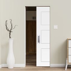 a white vase sitting next to a wooden cabinet on top of a hard wood floor