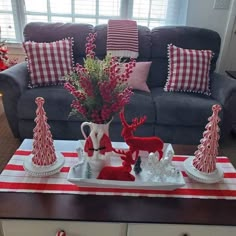 a living room decorated for christmas with red and white decorations on the coffee table in front of the couch