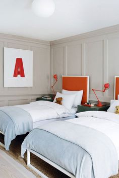 two beds in a room with white and orange headboards