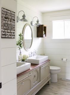 a bathroom with two sinks, a toilet and a large mirror above the sink in it