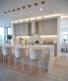 a kitchen with marble counter tops and bar stools next to an open floor plan