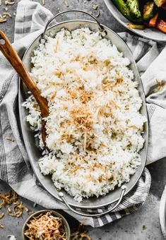 white rice with shredded parmesan cheese in a bowl on a towel next to a wooden spoon