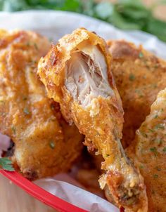 some fried food in a red basket on a wooden table with parsley sprinkled around it