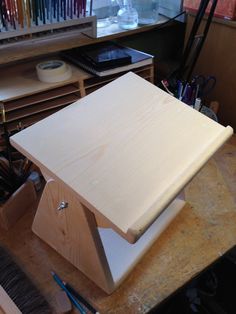 a wooden table topped with lots of crafting supplies next to a shelf filled with pens and pencils