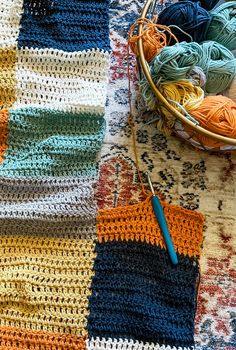 a basket full of yarn next to a crocheted afghan