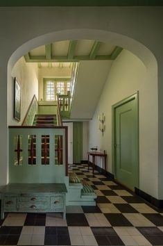 an archway leading to the second floor with a bench and checkerboard flooring