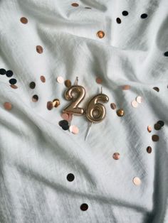 the number twenty six is surrounded by gold and black confetti on a white sheet