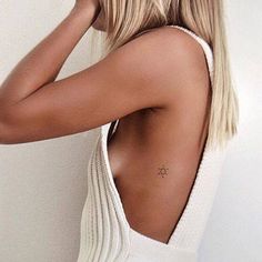 the back of a woman's head with her hand on her hair and wearing a white tank top