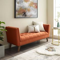 an orange couch sitting in front of a window next to a table and potted plant