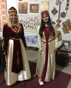 two women dressed in medieval costumes standing next to each other on a carpeted floor