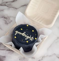 a cupcake in a box with the word goodnight written on it and gold stars