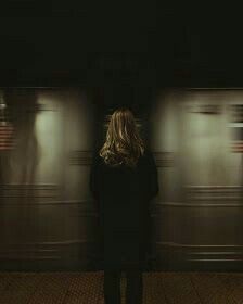 a woman standing in front of a wall with lights on it and her back to the camera