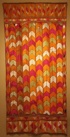 an orange and pink quilt hanging on the wall