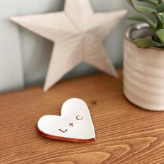 a ceramic heart sitting on top of a wooden table next to a potted plant