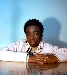 a young man sitting at a table with his hands on his chest and arms crossed