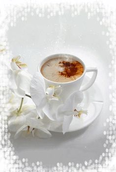 a cup of hot chocolate with white orchids