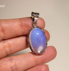 Step into the realm of celestial beauty with this enchanting Opalite gemstone pendant, delicately embraced by a sterling silver setting. Each facet of the Opalite captures the essence of the cosmos, radiating a luminous glow that mesmerizes the beholder and stirs the soul. --Setting including bail measures 38x18x8.5mm  --.925 Sterling Silver plated over copper setting, real gemstone Imagine a Opalite gemstone, shimmering with iridescent hues of blue, purple, and milky white. Nestled within a sterling silver setting, the Opalite seems to hold the secrets of the universe within its ethereal depths. As light dances across its surface, it creates a mesmerizing display of color and light, evoking the enchanting beauty of distant galaxies. Elevate your spiritual journey and adorn yourself with t Celestial Hallmarked Jewelry With Oval Stones, Celestial Style Hallmarked Oval Jewelry, Iridescent Oval Sterling Silver Jewelry, Iridescent Sterling Silver Spiritual Jewelry, Celestial Jewelry With Oval Natural Stones, Celestial Oval Jewelry With Natural Stones, Celestial Style Oval Jewelry With Natural Stones, Nickel-free Mystical Moonstone Jewelry, Silver Celestial Oval Jewelry