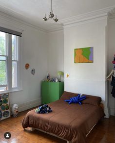 a bed room with a neatly made bed next to a window and a painting on the wall