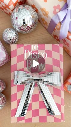 a pink and white box with a bow on it sitting next to disco balls in the background