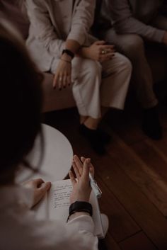 two people are sitting on a couch and one person is writing