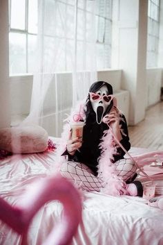 a woman in black and white is sitting on a bed with pink feathers around her