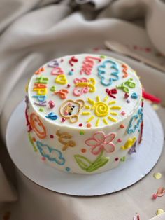 a decorated cake sitting on top of a white plate next to confetti sprinkles