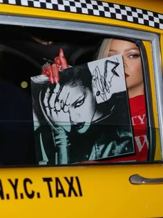 a taxi cab with the back window open and a person holding up a sign in front of it