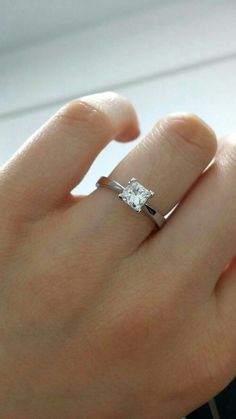 a woman's hand with a diamond ring on top of her finger and an engagement band