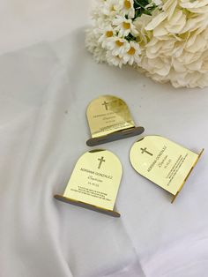 three pieces of paper with gold foil on them and a bouquet of flowers in the background