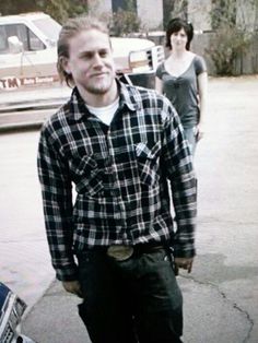 a man holding a skateboard while standing next to two women on the side walk